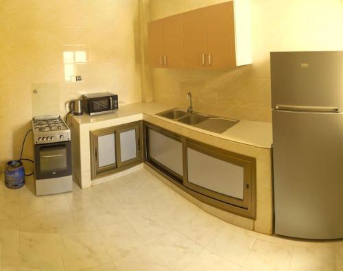 La cuisine est équipée d'un réfrigérateur, d'un évier et d'une cuisinière. dans l'établissement Superbe appartement F4 à Dakar Mermoz-Sacré cœur, à Dakar