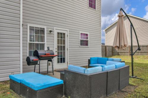 um pátio com comodidades para churrascos, cadeiras azuis e uma mesa em A Lush Retreat Amidst Greenery near Fort Stewart em Hinesville