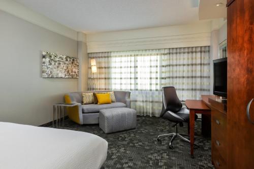 a hotel room with a bed and a couch and a desk at Courtyard by Marriott Houston Galleria in Houston