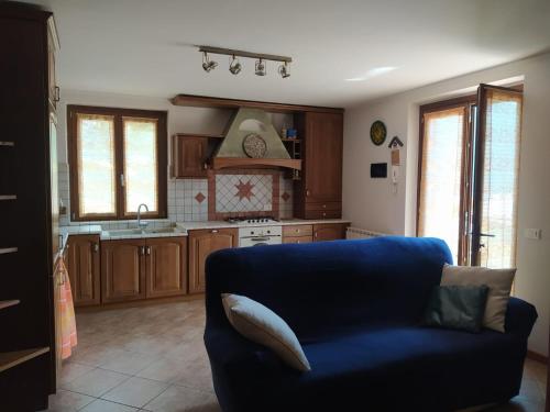 a living room with a blue couch and a kitchen at APPARTAMENTO PIEVE ANTICA 