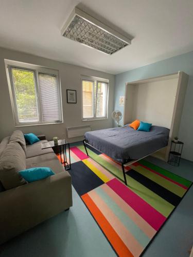 ein Schlafzimmer mit einem Bett und einem Sofa und einem bunten Teppich in der Unterkunft Happy place in Sarajevo