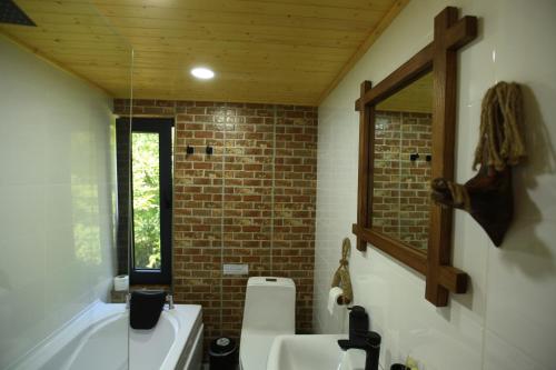 a bathroom with a white sink and a brick wall at Villa Vejini cabin in Mamkoda