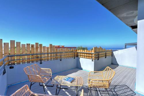 a balcony with chairs and tables and the ocean at La Terrasse - Apt T3 Saint Pierre in Saint-Pierre