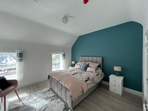 a bedroom with a bed with a blue wall at Sneem Studios in Sneem