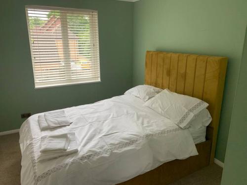 a bedroom with a bed with white sheets and a window at Cosy one bed flat free parking in Send