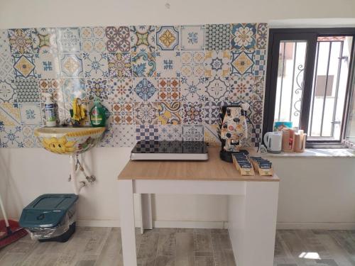 a kitchen with a table and a wall with tiles at Il Regno delle due Sicilie in Riposto