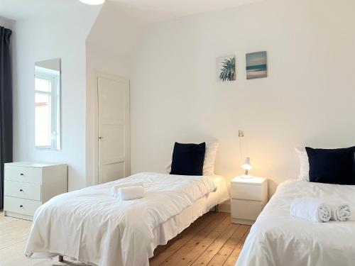 una camera con due letti con lenzuola bianche di Spacious 3 Bedroom Apartment With 2 Common Rooms a Vejle