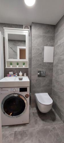 a bathroom with a washing machine and a toilet at DIVA contactless check in & out in Šiauliai