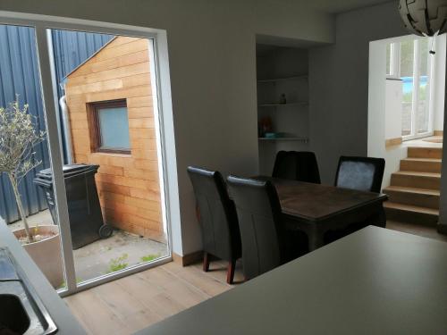 ein Wohnzimmer mit einem Tisch, Stühlen und einem Fenster in der Unterkunft Chambre cosy in Saint-Nicolas
