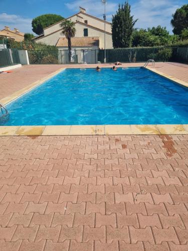 une grande piscine avec de l'eau bleue dans l'établissement Appartement proche mer avec jardin, à Saint-Cyprien