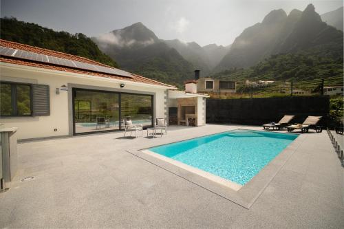a swimming pool in front of a house with mountains at Casa Avô da Pedra, By OP in São Vicente