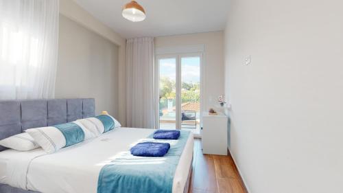 a bedroom with a bed with blue pillows and a window at Acrotel Porto Brava Luxury Villas in Ormos Panagias