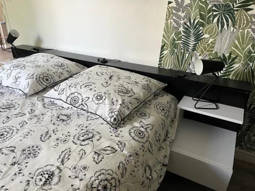 ein Bett mit einer schwarzen und weißen Bettdecke und Kissen in der Unterkunft L’Annexe in Chantelle