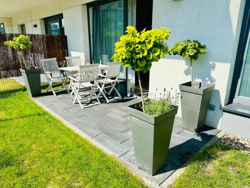 eine Terrasse mit drei Topfpflanzen sowie einem Tisch und Stühlen in der Unterkunft Przystań Letników by MYPART in your apartment in Danzig