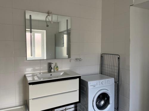 ein weißes Badezimmer mit einer Waschmaschine und einem Waschbecken in der Unterkunft L’Annexe in Chantelle