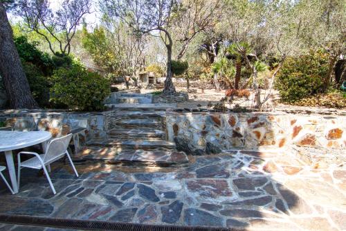 a stone patio with a table and chairs and trees at La Caseta de Cadaqués in Cadaqués