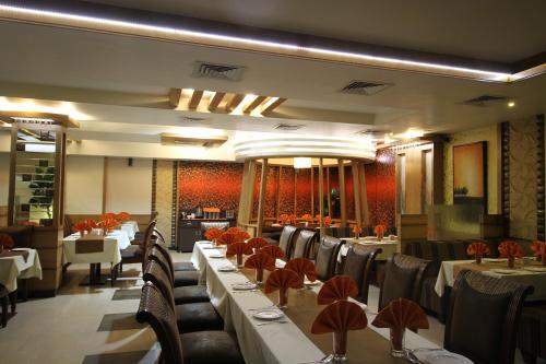 a dining room with tables and chairs in a restaurant at Hotel Meera in Raipur