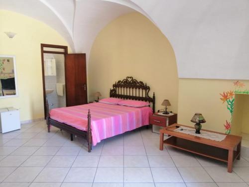 a bedroom with a pink bed and a table at TENUTA Li FRASULLI in Tuglie