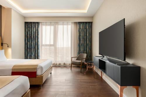 a hotel room with a bed and a flat screen tv at Ramada by Wyndham Karapinar in Karapınar