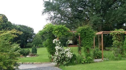 a garden with a wooden pergola and white flowers at Ancient Oaks Centre Val-De Loire-Culan in Saint-Saturnin