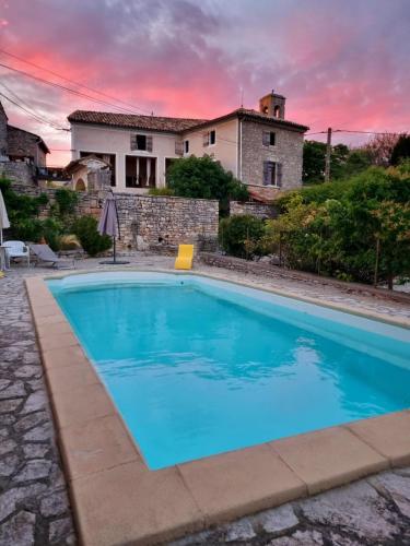 une grande piscine bleue devant une maison dans l'établissement Une Nuit au Village - chambre d'hôtes de charme, à Orgnac-lʼAven