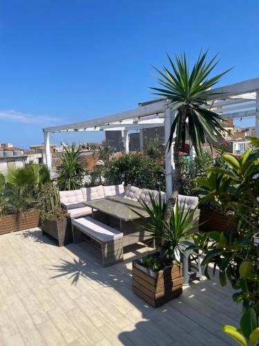 a patio with a bench and palm trees on a roof at Follow The Sun Catania - Rooftop Terrace in Catania