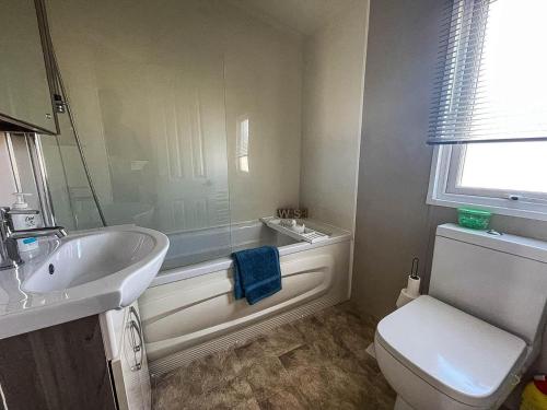 a bathroom with a tub and a sink and a toilet at Lovely Caravan With Decking At North Denes Park In Suffolk, Ref 40050nd in Lowestoft
