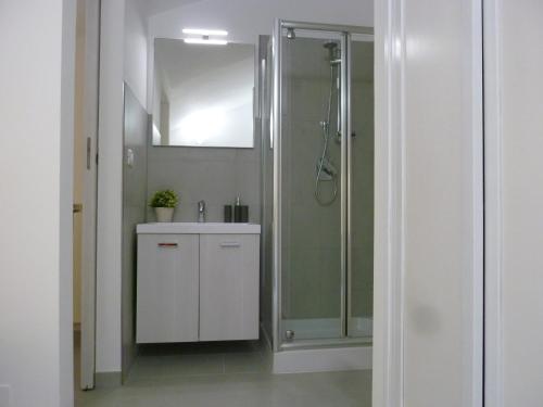 a bathroom with a shower and a sink and a mirror at Chà Apartment in Laigueglia