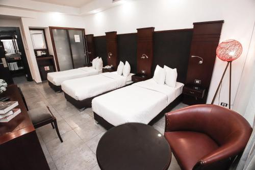 una camera d'albergo con tre letti e una sedia di Torino Hotel Amman ad Amman