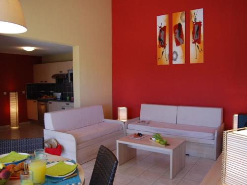 Elle comprend un salon doté d'un mobilier blanc et d'un mur rouge. dans l'établissement Holiday Home in France with Garden Terrace, à Torreilles