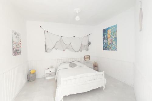a white bedroom with a bed and a banner at La Coquille in Sète