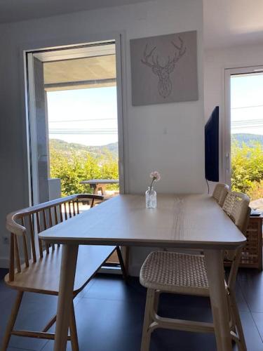 une table et des chaises dans une pièce avec une fenêtre dans l'établissement Appartement Gérardmer, à Gérardmer