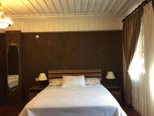 a bedroom with a large white bed with two lamps at Konak Lapeistra Hotel in Gure