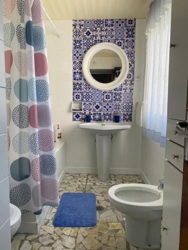 ein Badezimmer mit einem WC, einem Waschbecken und einem Spiegel in der Unterkunft Casa Ameixeira in Carnota