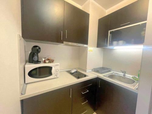a small kitchen with a microwave and a sink at Арборо Боровец Гардънс Д35 in Borovets