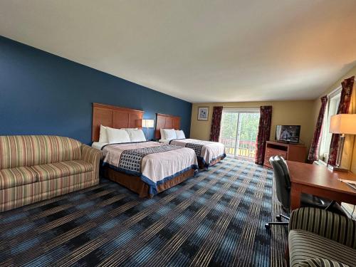 a hotel room with two beds and a desk at Swiss Chalets Village Inn in North Conway