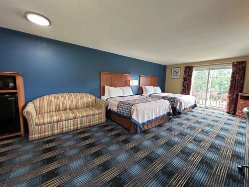 a hotel room with two beds and a chair at Swiss Chalets Village Inn in North Conway