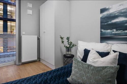a bedroom with a blue bed with pillows and a painting at Aker Brygge - Sjøside hjem - Sentral beliggenhet in Oslo