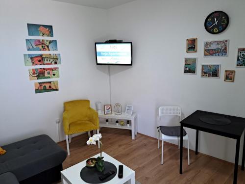 een woonkamer met een bank en een tv aan de muur bij Anja Apartman in Novi Sad