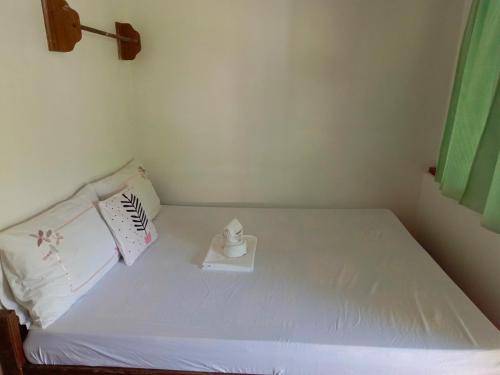 a small bedroom with a white bed with a candle on it at MiL's Hillside Tourist Inn in San Vicente