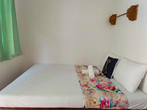 a bedroom with a bed with a flower blanket on it at MiL's Hillside Tourist Inn in San Vicente