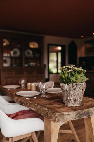a wooden table with plates and a vase of flowers on it at La Villa Ava in Somme-Leuze