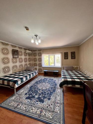 two beds in a room with a rug at InJoy Hostel in Shymkent