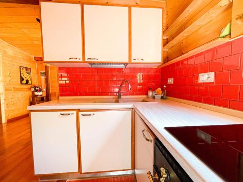 a kitchen with white cabinets and red tiles at Le sorgenti - Chalet 12 in Palazzuolo sul Senio