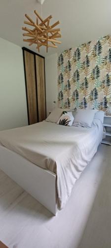 a bedroom with a large white bed and a chandelier at Gîte Du Bas Bagneux, 7 kms du Zoo de Beauval - parking gratuit in Mareuil-sur-Cher
