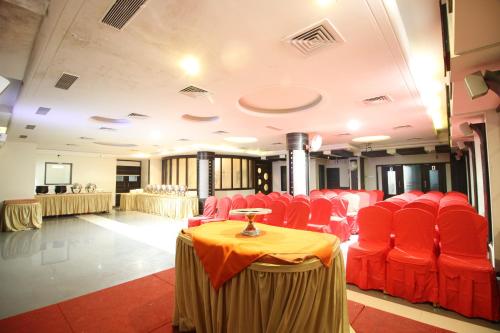 a room with red chairs and a table and a screen at Hotel Meera in Raipur