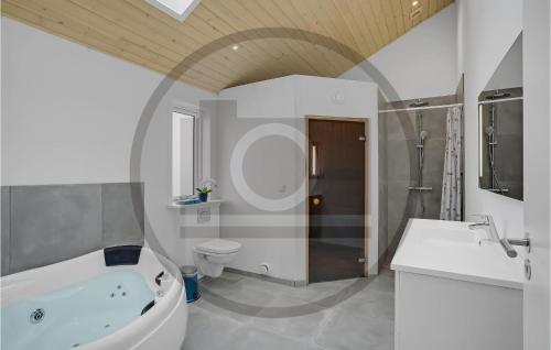 a bathroom with a tub and a toilet and a sink at 4 Bedroom Cozy Home In Ebeltoft in Ebeltoft