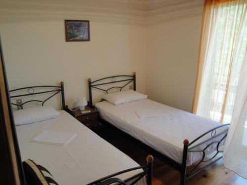 two twin beds in a room with a window at Paschos Rooms in Syvota