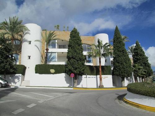 ein weißes Gebäude mit Bäumen vor einer Straße in der Unterkunft Apartamento Relax y Golf in Mijas