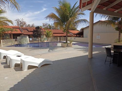 a patio with white benches in front of a pool at CASA em CALDAS NOVAS in Caldas Novas